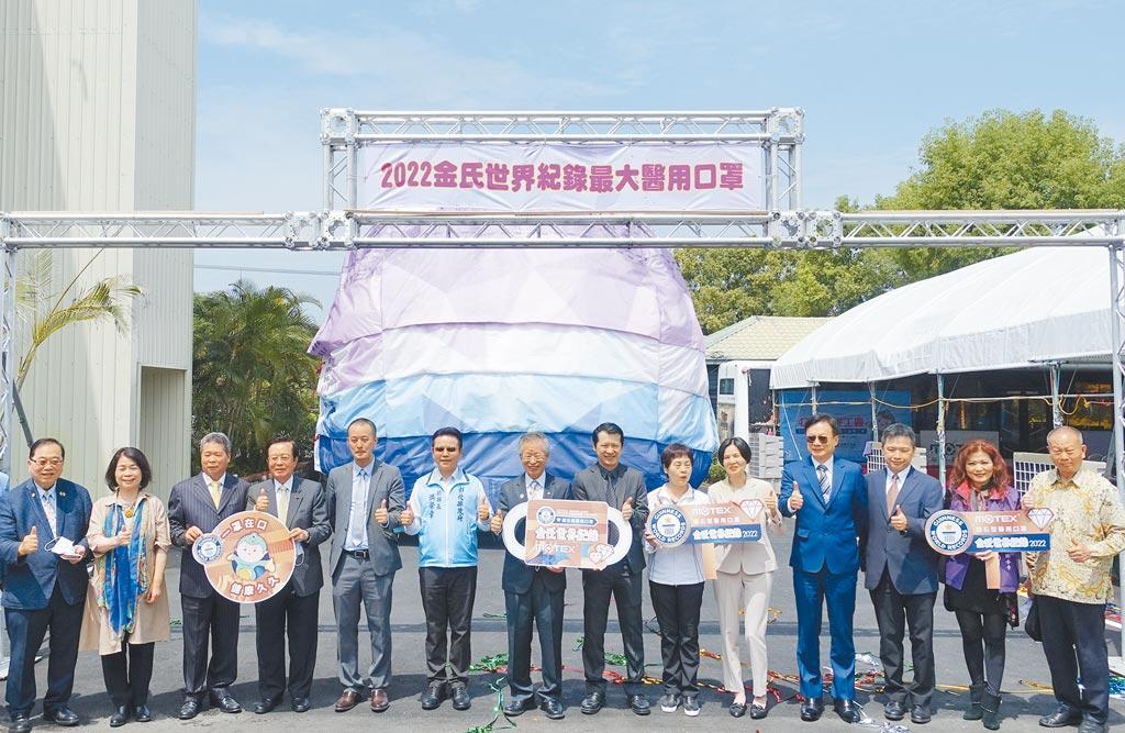 華新醫材集團慶祝「金氏世界紀錄最大醫療（鑽石型）口罩」挑戰成功，董事長鄭永柱（右八）和與會貴賓在最大醫療口罩前合影。圖／黃俊榮