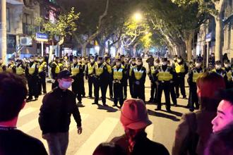 BBC記者勞倫斯（Ed Lawrence）27日在上海採訪反封控抗議現場時，遭到上海警察拳打腳踢並關押數小時後才釋放。圖為27日上海警察封鎖抗議現場。（圖／美聯社）