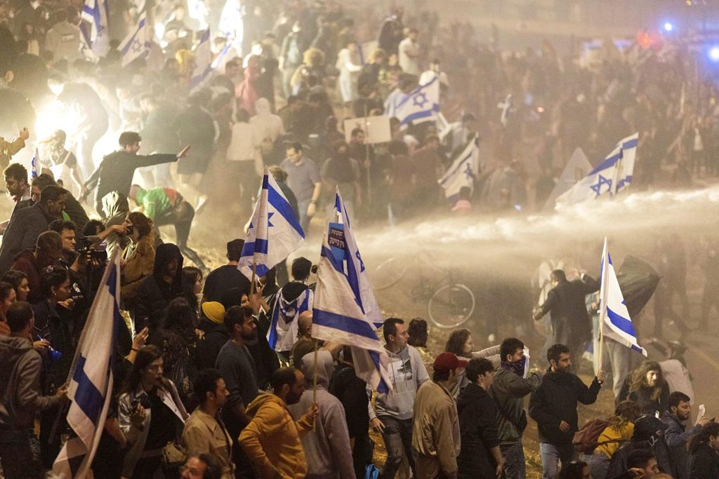 上萬以色列人26日深夜霸占特拉維夫一座高速公路抗議，遭到警方以強力水柱驅逐。（圖／美聯社）
