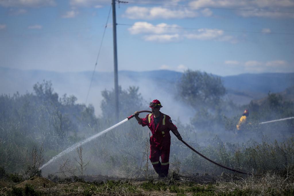 2023年6月5日一名消防員在加拿英屬哥倫比亞省坎盧普斯的一處住宅區後面的一塊土地上滅火。（美聯社）