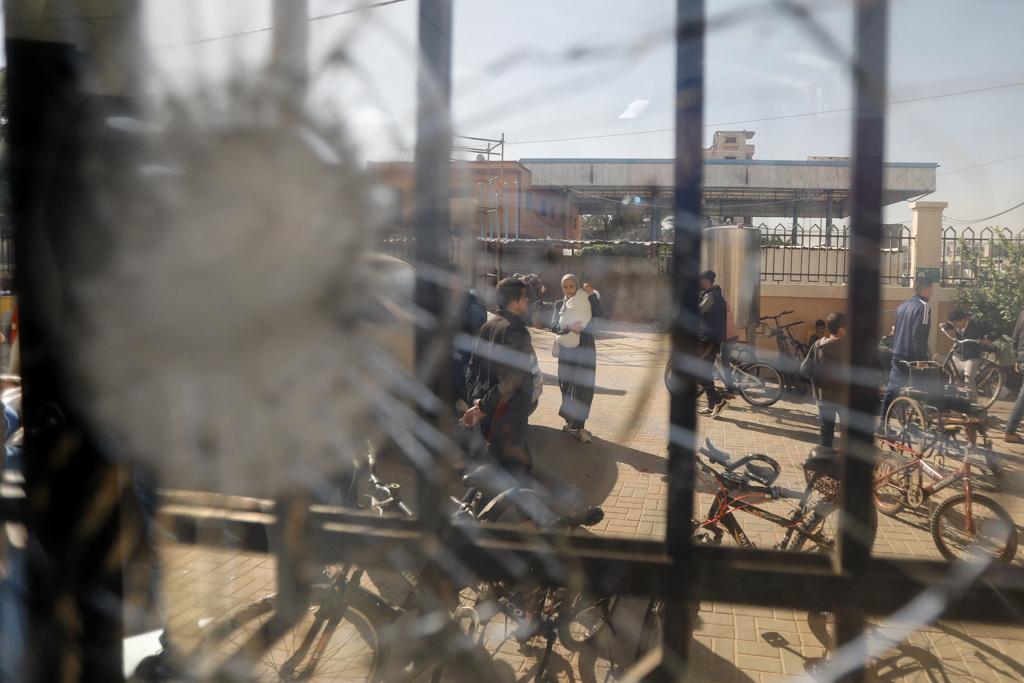 加薩走廊南部大城甘尤尼斯（Khan Younis）的巴勒斯坦人，29日行經一處保健中心，窗戶玻璃因戰火龜裂。（路透）