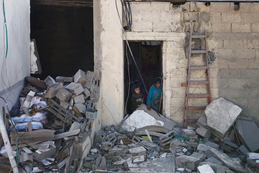 加薩走廊南部靠近埃及邊境的城市拉法（Rafah），民宅遭以色列砲火炸得面目全非，倖存兒童站在殘破家園門口無所適從。（路透）